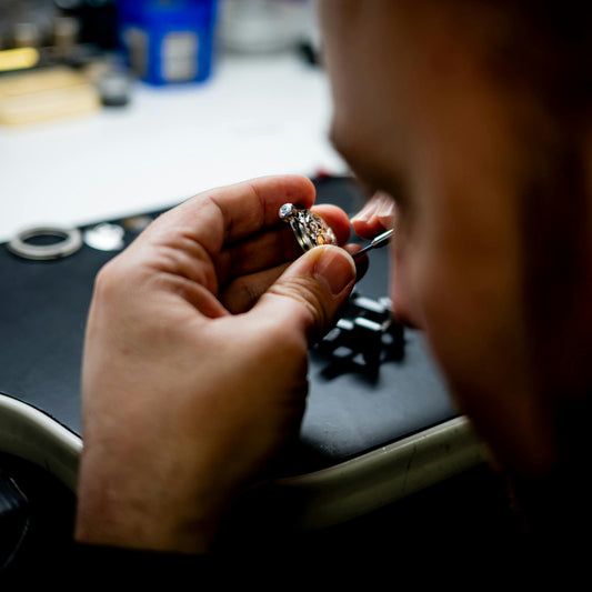 Person examining a ring with a close-up of their hands on a desk.